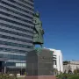 Marco Polo statue on a stone pedestal in front of a modern building.