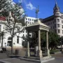 Temperance Fountain in a city square, with a stone pavilion and bird statue above it.