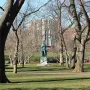 William the Silent bronze statue on a stone base in a grassy setting with leafless trees and a large building in the background