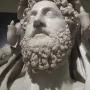 Close-up of the marble bust of Commodus as Hercules with a curly beard and lion skin draped over the shoulders.