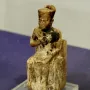 Khufu statuette showing a seated figure wearing a tall rectangular headdress on a clear base.