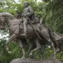 Robert E. Lee equestrian statue with a bearded rider on horseback, raising his hat, and a second mounted figure behind him.
