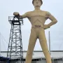 Golden Driller statue standing beside an oil derrick model in Tulsa