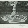 The Lorelei Fountain, a stone fountain with a standing figure on a tall pedestal and smaller figures in a stepped basin, set in a wooded park.