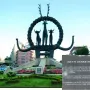 Hittite Sun Disk Monument with animal figures on a landscaped base in an urban setting.