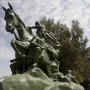 Low-angle view of the Saladin equestrian statue, showing a bronze warrior on a rearing horse above smaller figures on a rock-like base.