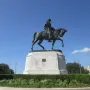 Gen. Beauregard equestrian statue on a tall stone pedestal, surrounded by hedges and flowers.