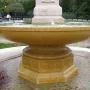 Butt–Millet Memorial Fountain with a shallow stone bowl, carved inscriptions, and an octagonal base in a pebbled basin.