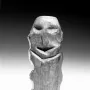 Mannetje van Willemstad wooden carving with carved facial features against a dark background.