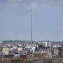 The Spire rises above Dublin rooftops and buildings under a cloudy sky.