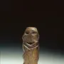 Mannetje van Willemstad wooden carving with carved facial features against a dark background.