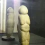 Venus of Chiozza figurine displayed on a dark circular base inside a case.