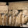 Marble relief slab from the Plutei of Trajan showing carved livestock in front of ancient Roman ruins.