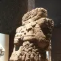 Coatlicue stone statue with serpent heads, skull necklace, and carved textured body