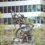 Mechanics Monument bronze sculpture of muscular men operating industrial machinery on a stepped stone pedestal.