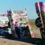 Cadillac Ranch with several vintage Cadillacs buried nose-down in a dusty field and covered in colorful graffiti.