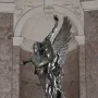 Gloria Victis bronze sculpture showing a winged figure supporting a dying warrior against a marbled wall.