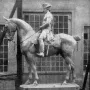 The Equestrian Monument of Frederick the Great shown as a large equestrian statue on a simple base in front of a building with many windows.