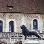The Brunswick Lion statue stands on a stone pedestal in front of a historic stone building.