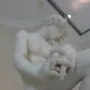 The Exiled, a white marble sculpture of a seated male figure with bowed head and clasped hands.