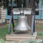 The Liberty Bell displayed on a wooden platform with a dark metal frame, surrounded by trees and ground cover.