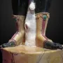 Close-up of the Moor of Borghese statue showing the lower legs, bare feet, and carved boots above a marbled pedestal.