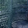 Kryptos, a curved metal sculpture covered with cut-out letters and numbers, with patterned shadows cast on the ground.