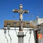 Christ of the Lanterns crucifix with ornate lanterns and a spiked fence in front of a white building