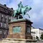 Frederick VII equestrian statue on a tall stone pedestal in a city square.