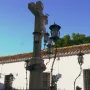 Christ of the Lanterns crucifix with ornate lanterns and a spiked fence in front of a white building