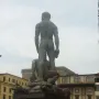Hercules and Cacus seen from behind, with the muscular standing figure atop another figure on an ornate pedestal.