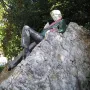 Oscar Wilde Memorial Sculpture of a reclining figure with light hair on a large rocky boulder.
