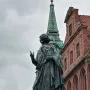 Nicolaus Copernicus Monument in Toruń, a bronze robed figure pointing upward with a celestial sphere in hand.