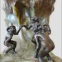 The Wave sculpture with three dark bronze nude figures holding hands on a veined stone base.