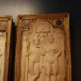 Queriniano Diptych ivory panel with a carved standing man and woman, a cherub, and a small animal beneath a shell-topped arch.