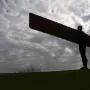 The Angel of the North sculpture standing on a grassy hill against a cloudy sky.