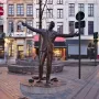Jacques Brel memorial bronze statue by Tom Frantzen, shown with arms outstretched on a cobblestone square in Brussels.