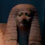 Head and upper torso of Amenia sculpture with heavily lidded eyes and a large textured wig