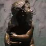 Candelabra Angels, a bronze winged putto seated on an ornate white base and holding a small object while looking upward.