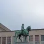 Albert I equestrian statue on a stone pedestal in a public square, with buildings and steps in the background.