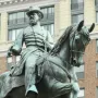 General James B. McPherson equestrian statue in bronze with a green patina, shown against a tall brick building.