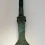 The Spear of Lugal, a tarnished metal artifact with an engraved feline figure and three holes in the handle.