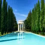 Pulgas Water Temple with a long blue reflecting pool, stone rotunda, and tall evergreen trees lining the avenue.