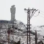 Statue of Humanity, a towering concrete sculpture of two abstract human figures beside a circular building in snowy Kars.
