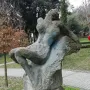 Güzel İstanbul sculpture showing a gray, reclined stone figure in a grassy park near a paved path.
