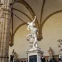 The Rape of the Sabine Women marble sculpture shows three intertwined figures in a dynamic pose inside an arched loggia.