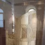 Throne of Maximian with a high arched back and ornate relief carvings inside a glass case.