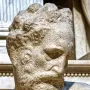 Close-up of Michelangelo’s Medici Chapel sculpture showing a bearded male figure with his head angled downward.
