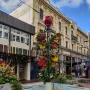 The Bucket Fountain sculpture in a light blue basin, decorated with colorful flower-filled buckets and a red sphere on top.
