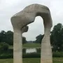 Henry Moore\'s The Arch stands on grass, framing water and distant trees under an overcast sky.